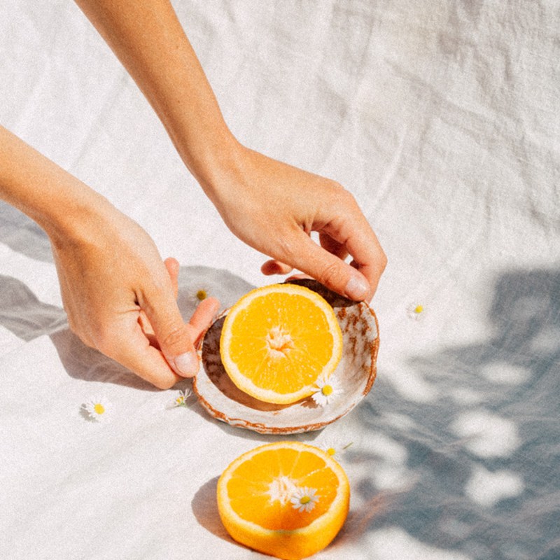 Mains tenant une coupelle d’orange sur un linge blanc