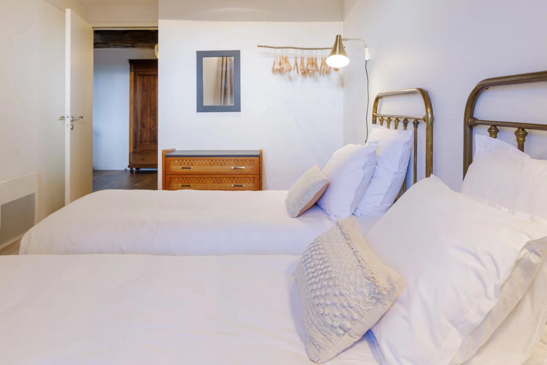 Chambre à deux lits en laiton, linge blanc, lumière douce