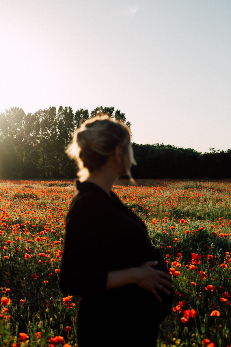 Femme seule dans un champ de coquelicots au soleil couchant