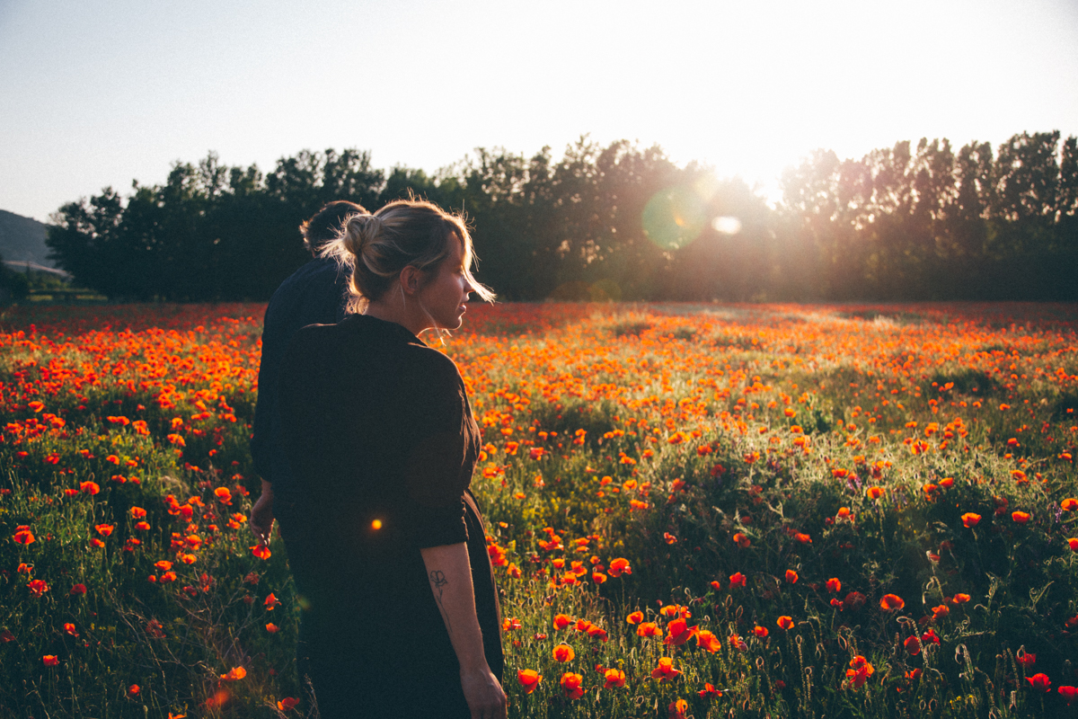 Femme dans un champ de coquelicots au soleil couchant
